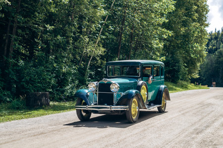 Chambord, Canada - August 18, 2025: Green vintage car with waving person during event at Val-Jalbert Historical Village in Quebecのeditorial素材