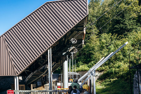 Chambord, Canada - August 18, 2025: White and red aerial tram car hanging from cables against forest at Val-Jalbert Historical Village in Quebecのeditorial素材