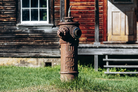 Chambord, Canada - August 18, 2025: Vintage rusted fire hydrant near abandoned wooden houses at...