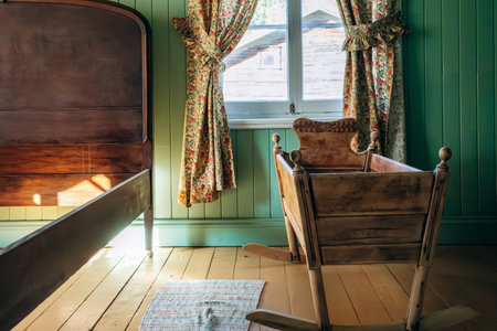 Chambord, Canada - August 18, 2025: Restored 1927 bedroom interior with wooden cradle and floral curtains at Val-Jalbert Historical Village in Quebecのeditorial素材