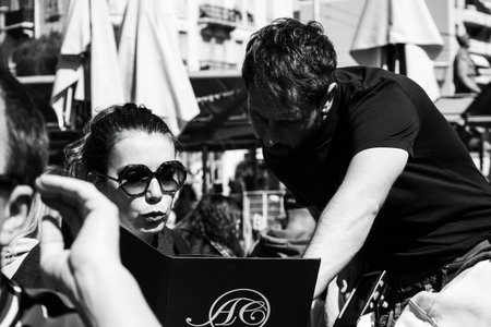 Nice, France - March 23, 2025: Waiter talking with a female customer at an outdoor cafe at Liberation market in Niceのeditorial素材