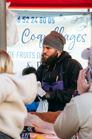 Nice, France - March 23, 2025: Market vendor serving customers at the Liberation street market on a Sunday morningのeditorial素材