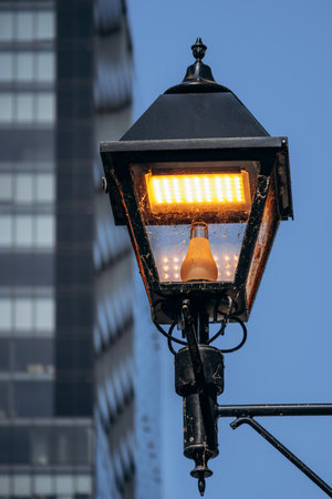 A softly blurred vintage-style street lamp in downtown Montreal with modern glass skyscrapers in the...