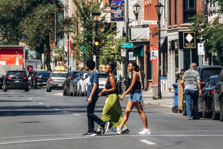 Montreal, Canada â€“ August 12, 2025: Three pedestrians crossing the street at a crosswalk in...