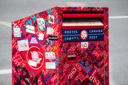 Montreal, Canada - August 14, 2025: A bright red Canada Post mailbox covered with colorful stickers,...