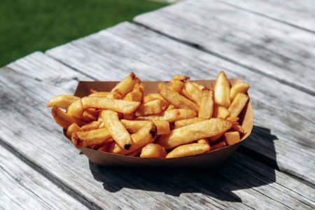 Fresh french fries in a paper tray outdoors