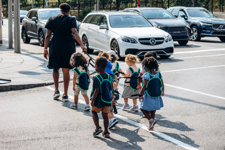 Montreal, Canada - August 14, 2025: two caregivers safely escort a group of preschool children across downtown streetのeditorial素材