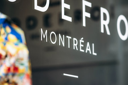 Montreal, Canada - August 14, 2025: Storefront window with Montreal sign and part of colorful shirt...