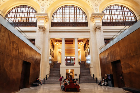 Ottawa, Canada - August 13, 2025: Grand interior hall of the Senate of Canada Building with high arched windows, clock, marble columns, and visitors sitting and walking in the spacious lobby.のeditorial素材