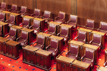 Ottawa, Canada â August 13, 2025: Rows of traditional wooden desks and burgundy leather chairs inside the Senate Chamber at the Senate of Canada Building, showcasing the historic designのeditorial素材