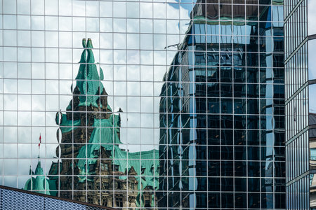 Ottawa, Canada - August 13, 2025: Reflection of the historic Confederation Building in the glass facade of a modern office tower in downtown Ottawaのeditorial素材