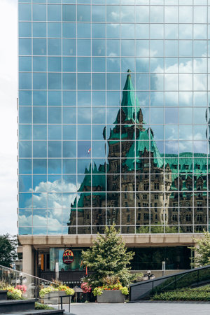 Ottawa, Canada - August 13, 2025: Reflection of the historic Confederation Building in the glass facade of a modern office tower in downtown Ottawaのeditorial素材
