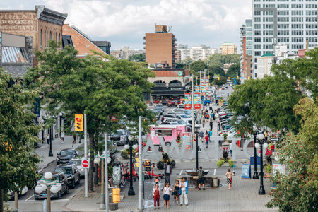 Ottawa, Canada - August 13, 2025: Busy downtown street scene in central Ottawa with the OTTAWA sign, pedestrians, traffic, trees, shops, and mid rise buildings under a cloudy summer sky.のeditorial素材