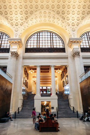 Ottawa, Canada - August 13, 2025: Grand interior hall of the Senate of Canada Building with high arched windows, clock, marble columns, and visitors sitting and walking in the spacious lobby.のeditorial素材