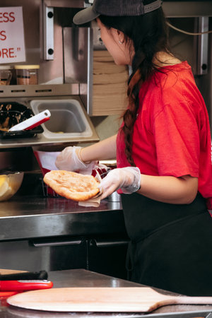 Ottawa, Canada - August 13, 2025: Staff member preparing a fresh Beavertail pastry inside the Beavertails kioskのeditorial素材