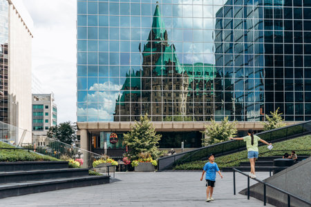 Ottawa, Canada - August 13, 2025: Reflection of the historic Confederation Building in the glass facade of a modern office tower in downtown Ottawaのeditorial素材