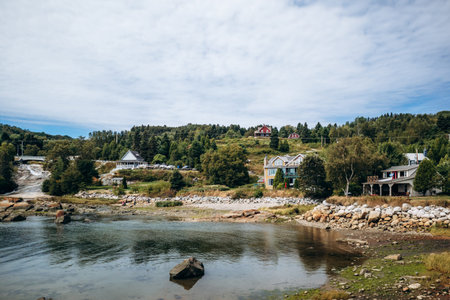 Coastal village houses and small bridge along the Saint Lawrence River with forested hills in Quebec, Port-au-Persil, Canadaの写真素材