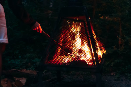 Man tending a night campfire beside a tiny house in the forest near Saguenay, Quebecの写真素材