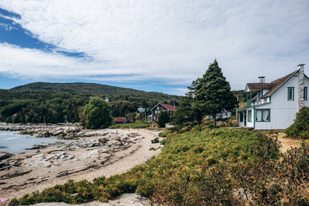 Sandy beach and rocky shoreline with gentle waves along the Saint Lawrence River in rural Quebec village, Port-au-Persil, Canadaの写真素材