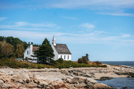 Port-au-Persil, Canada - August 20, 2025: Small white wooden chapel with bell tower overlooking the...