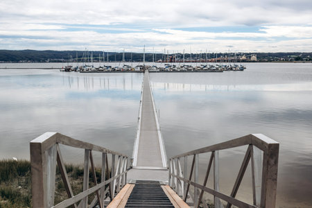 La Baie, Quebec, Canada â€“ August 19, 2025: Wooden pier leading to a marina with moored...