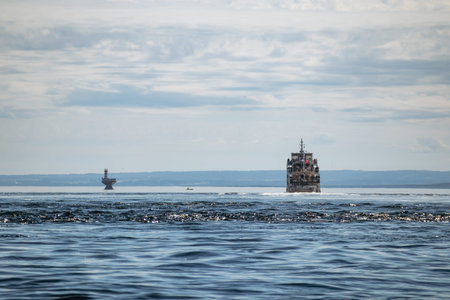 Passenger ferry navigating the St Lawrence River with a red navigation buoy in the distance under a dramatic cloudy skyの写真素材