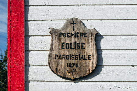 Wooden plaque reading âPremiere Eglise Paroissiale 1876â (First Parish Church 1876) on the facade of a historic building at Village historique de Saint Firmin (Saint Firmin Historic Village)の写真素材