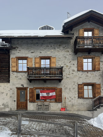 Livigno, Italy - February 18, 2026: Austrian flag on traditional alpine house during Milano Cortina 2026 Winter Olympic Games in snowy mountain townのeditorial素材