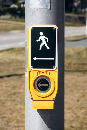 La Malbaie, Canada - August 22, 2025: Pedestrian crossing push button with walking symbol and...
