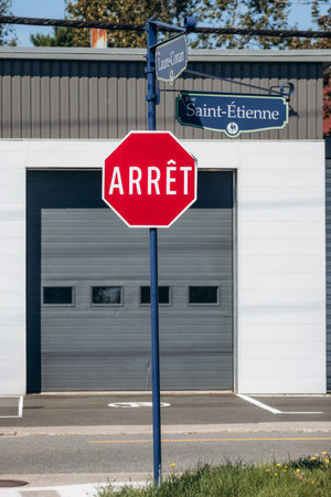 La Malbaie, Canada - August 22, 2025: French stop sign reading Arret with street signs for Rue Saint...