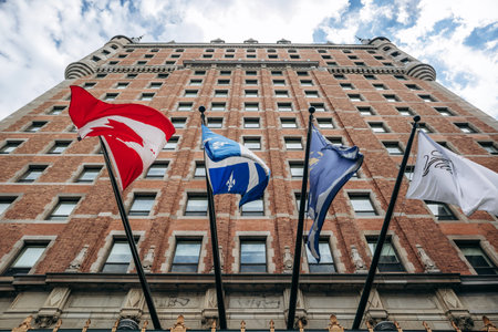 Quebec City, Canada - August 23, 2025: Fairmont Le Chateau Frontenac hotel entrance with Canadian and Quebec flags on flagpoles against historic brick facade seen from belowのeditorial素材