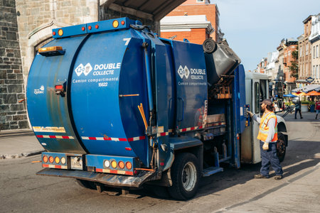 Quebec City, Canada - August 24, 2025: Municipal garbage truck collecting waste on a street in Old...