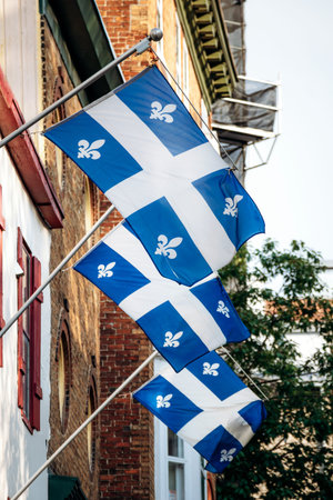 Quebec City, Canada - August 24, 2025: Quebec provincial flags with fleur-de-lis hanging on historic...