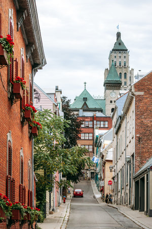 Quebec City, Canada - August 24, 2025: Historic street with colorful buildings and church towers in...