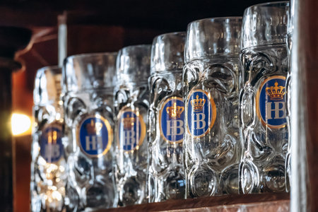 Munich, Germany - April 15, 2025: Traditional Hofbrauhaus beer mugs displayed on wooden shelves...