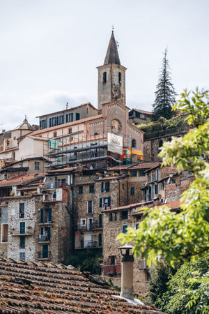 Apricale, Italy - April 26, 2025: View of historic stone houses and the church of San Bartolomeo with bell tower in the hilltop village of Apricale, Liguriaのeditorial素材