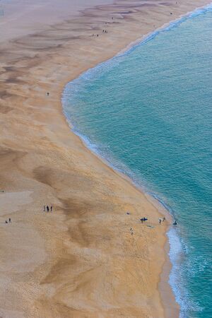 Peniche beach seen from the top of the slope in winter with some surfers entering the waterの写真素材