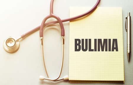 On a purple background a stethoscope and pen with yellow list with text BULIMIAの写真素材