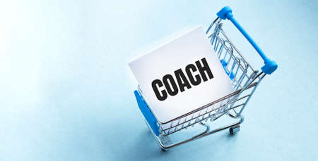 Hand pushing miniature toy supermarket trolley. White background. training TEXT Shopping concept.の写真素材