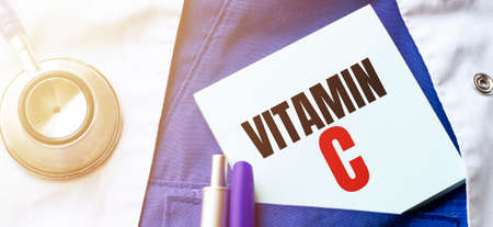 Doctor robe, stethoscope, pens and note with text VITAMIN Cの写真素材