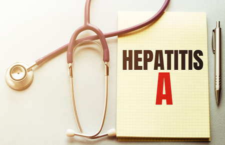 On a purple background a stethoscope and pen with yellow list with text HEPATITIS Aの写真素材