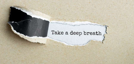 The text TAKE A DEEP BREATH appearing behind torn brown paperの写真素材