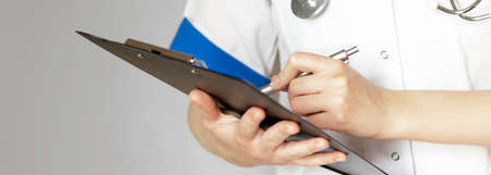 Hand of female doctor with pen writing on prescription blankの写真素材