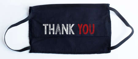 Black disposable protective mask with THANK YOU text on black background.の写真素材