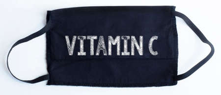 Black disposable protective mask with vitamin c text on black background.の写真素材