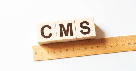 CMS letters of wooden blocks in pillar form on white background, copy spaceの写真素材