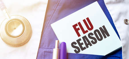 Doctor robe, stethoscope, pens and note with text flu seasonの写真素材
