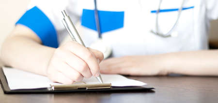 Hand of female doctor with pen writing on prescription blankの写真素材