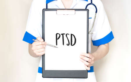 Doctor holding a card with text PTSD, medical conceptの写真素材