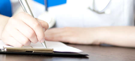 Hand of female doctor with pen writing on prescription blank